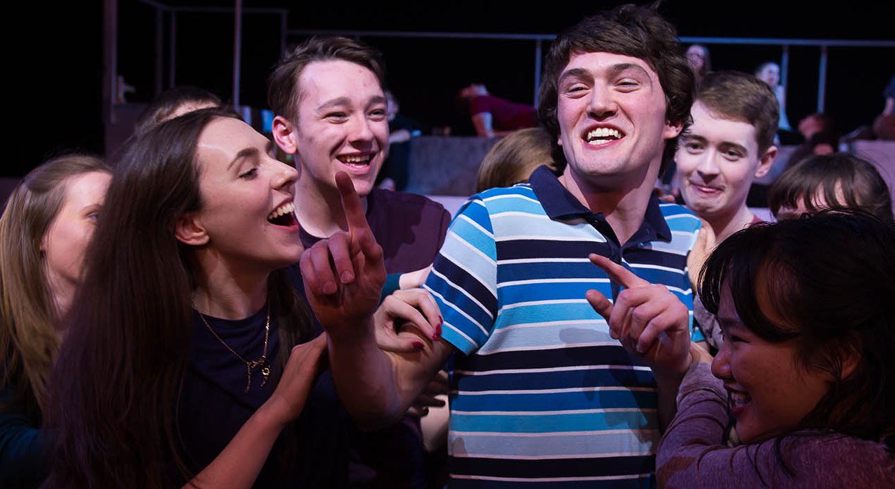 A man with a blue stripy holding his fingers up in the air