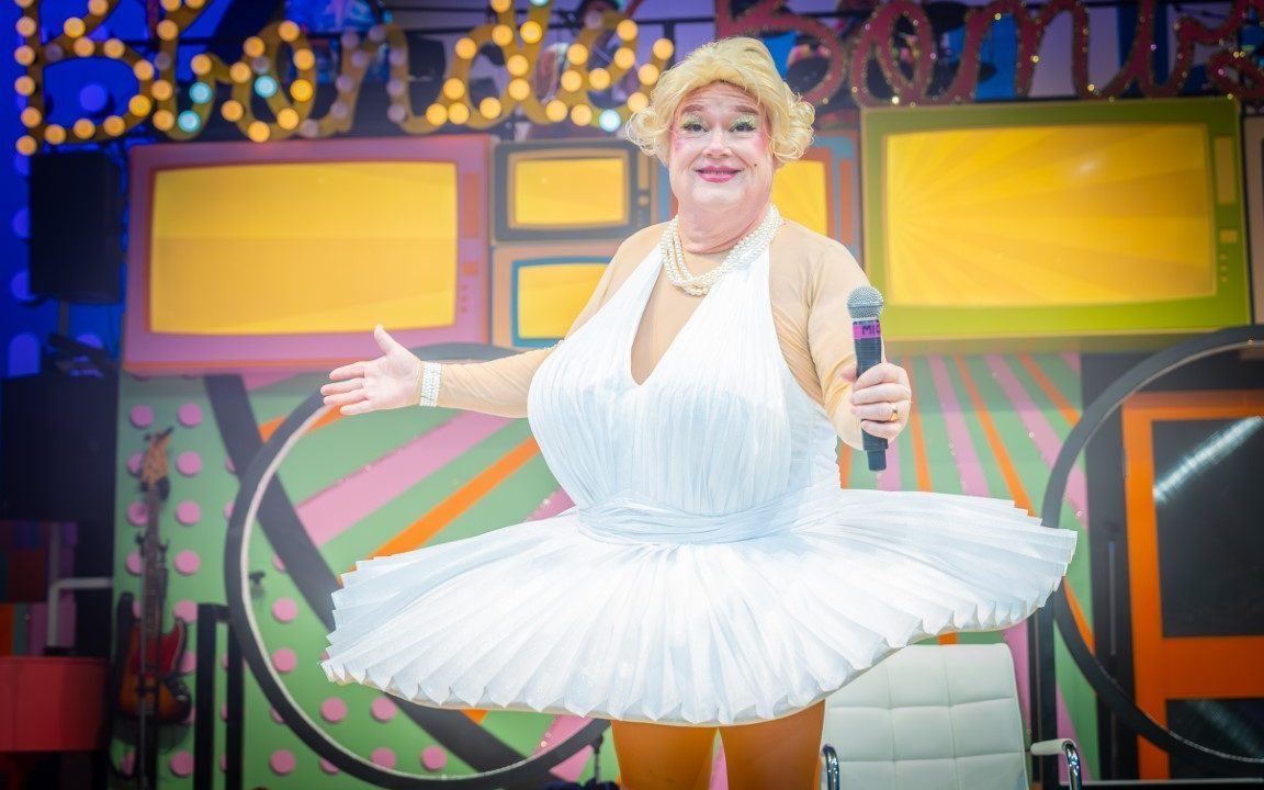 A person wearing a white floaty dress with an enlarged chest. They have a Marilyn Monroe inspiration.