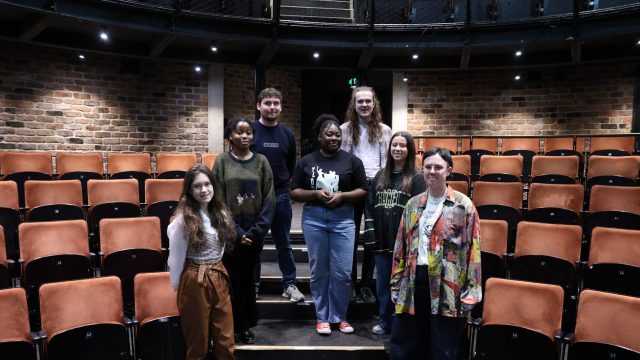 a group of young people stand on the steps of an auditorium