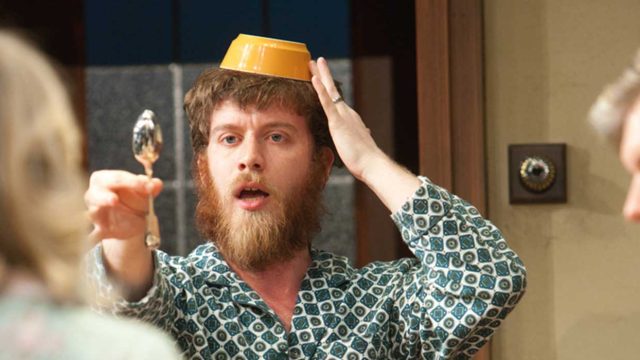 A man with a bowl on his head holding up a teaspoon