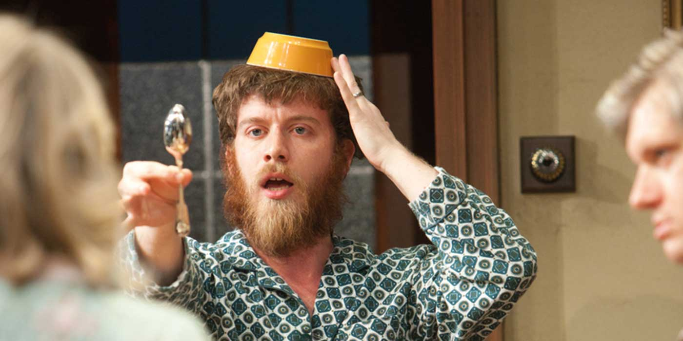 A man with a bowl on his head holding up a teaspoon