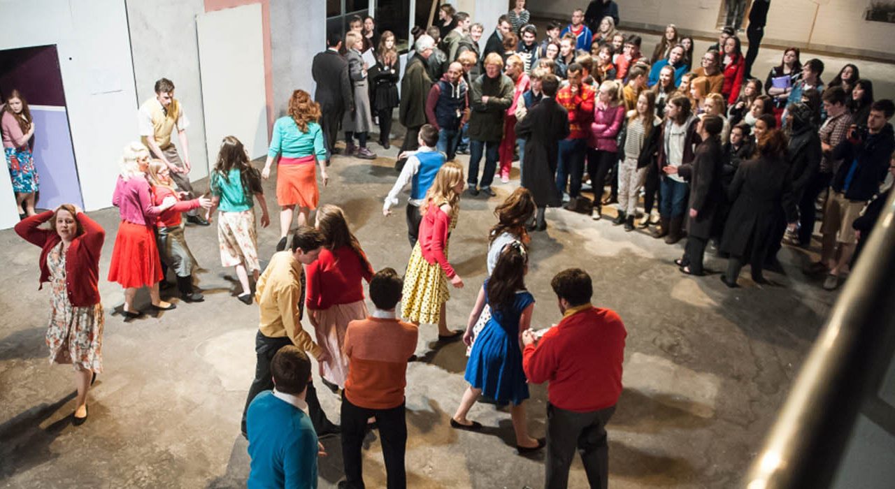 Two groups of people. One group has bright coloured clothing and one with dreary office wear