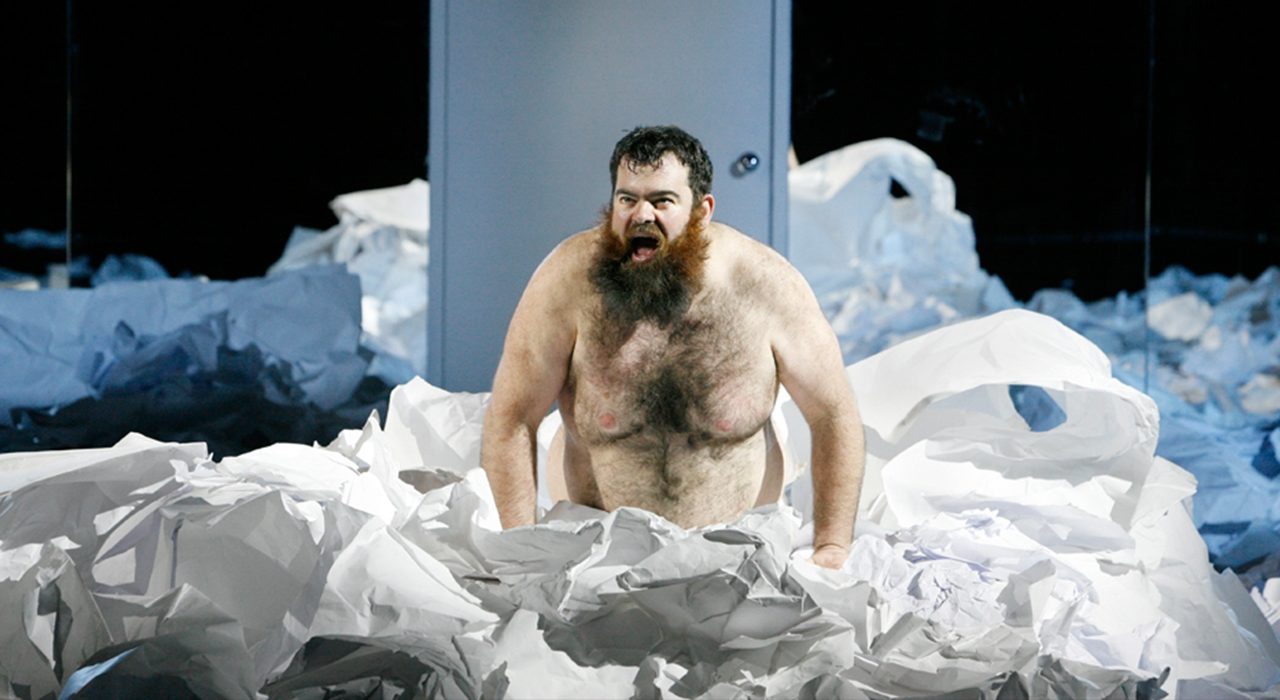 A topless man in a sea of paper