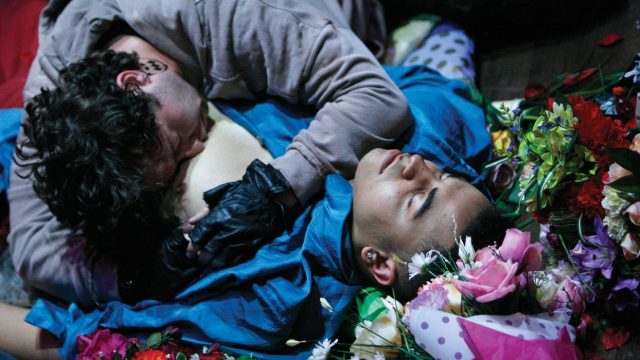 A person lying on the floor with another person lying on their chest