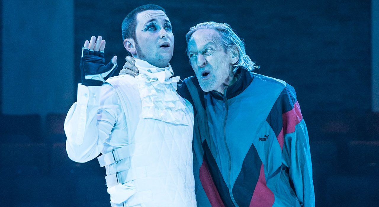 A man wearing boiler suit and a man in a multi colour anorak