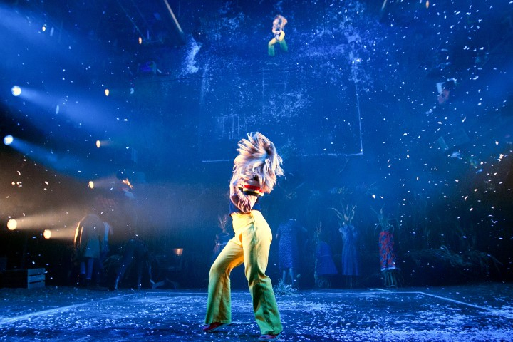 A woman wearing Yellow flares is shaking her hair center stage as confetti falls