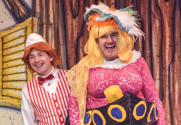 Two people stood next to each other. One is dressed as an ice-cream server with a red striped wasitcoat and red bow tie. The other has long blonde hair and a pink dress on