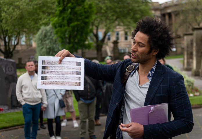 A man holding a printout of old hand writing infront of st Georges hall on the walking tour