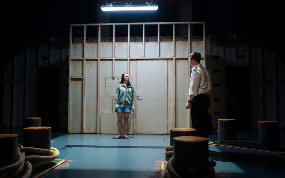 A man and a woman having a onversatioin in a back room of a boat.