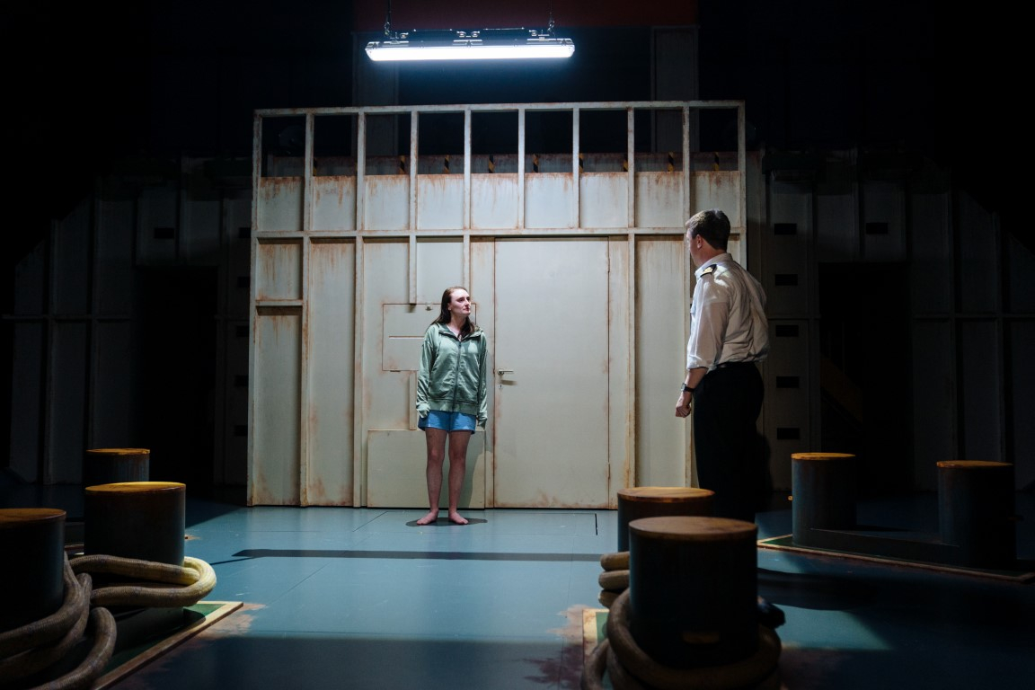 A man and a woman having a onversatioin in a back room of a boat.