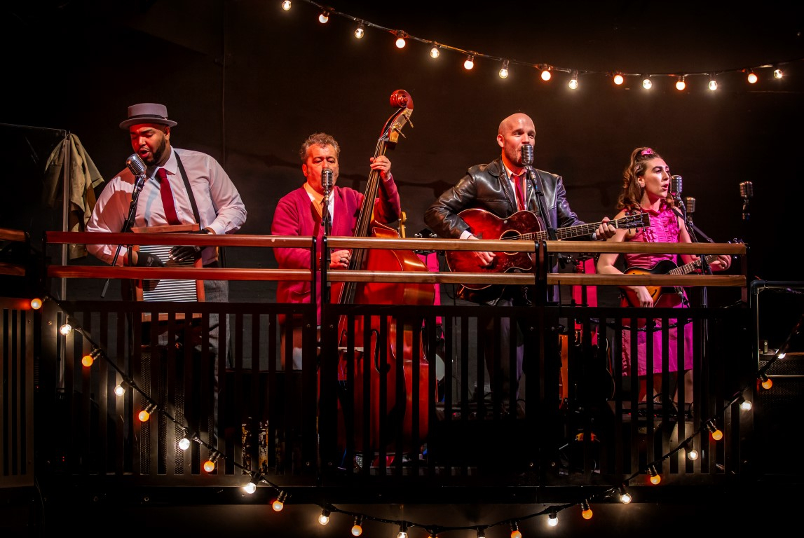 A four piece live band containing a musical wash board, cello, an acoustic and electric guitar