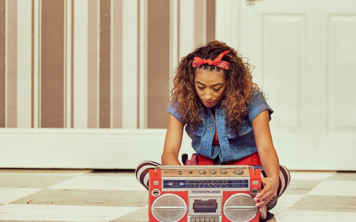 Alice sat on the floor with her legs crossed staring at a red boombox