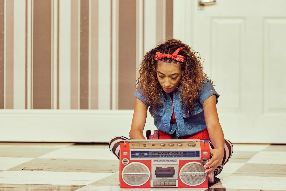 Alice sat on the floor with her legs crossed staring at a red boombox