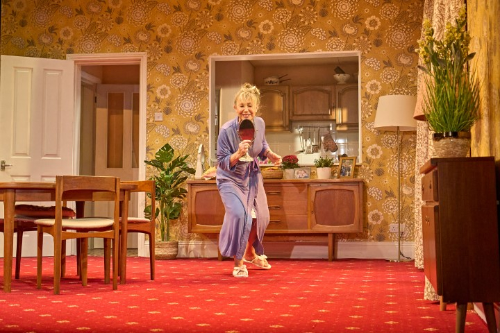 A woman in a living room singing into a dressing table mirror