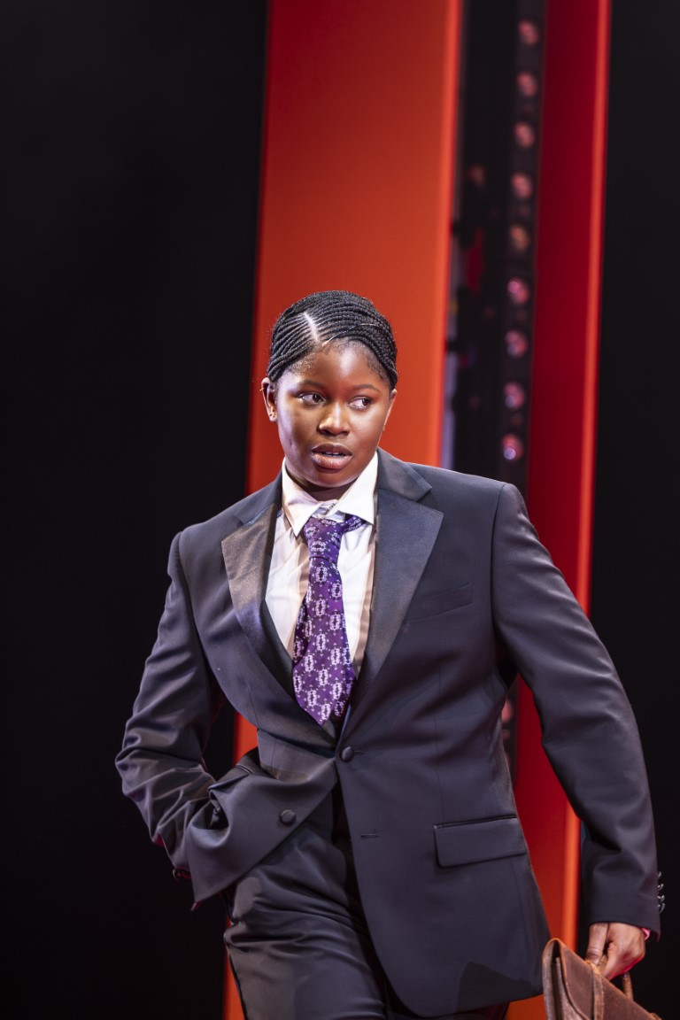 A person wearing a suit with a purple tie holding a brief case