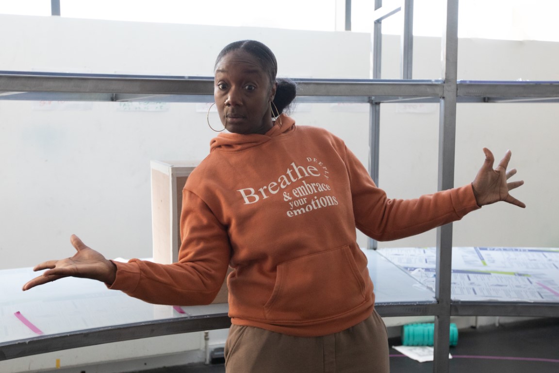 A woman in an orange hoodie stood with her arms out to the sides