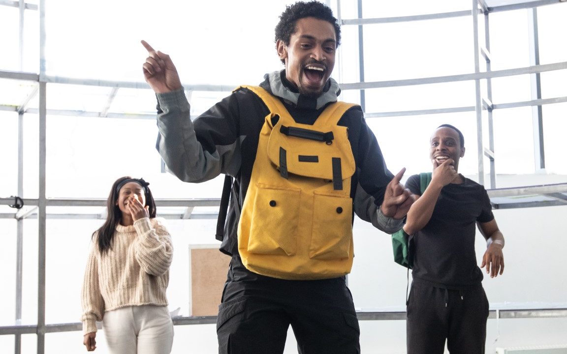 A man wearing a yellow backpack on his front pointing to the side